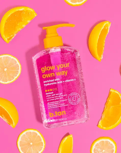 b.tan glow your own way flaske placeret på en pink baggrund omgivet af citron skiver. 